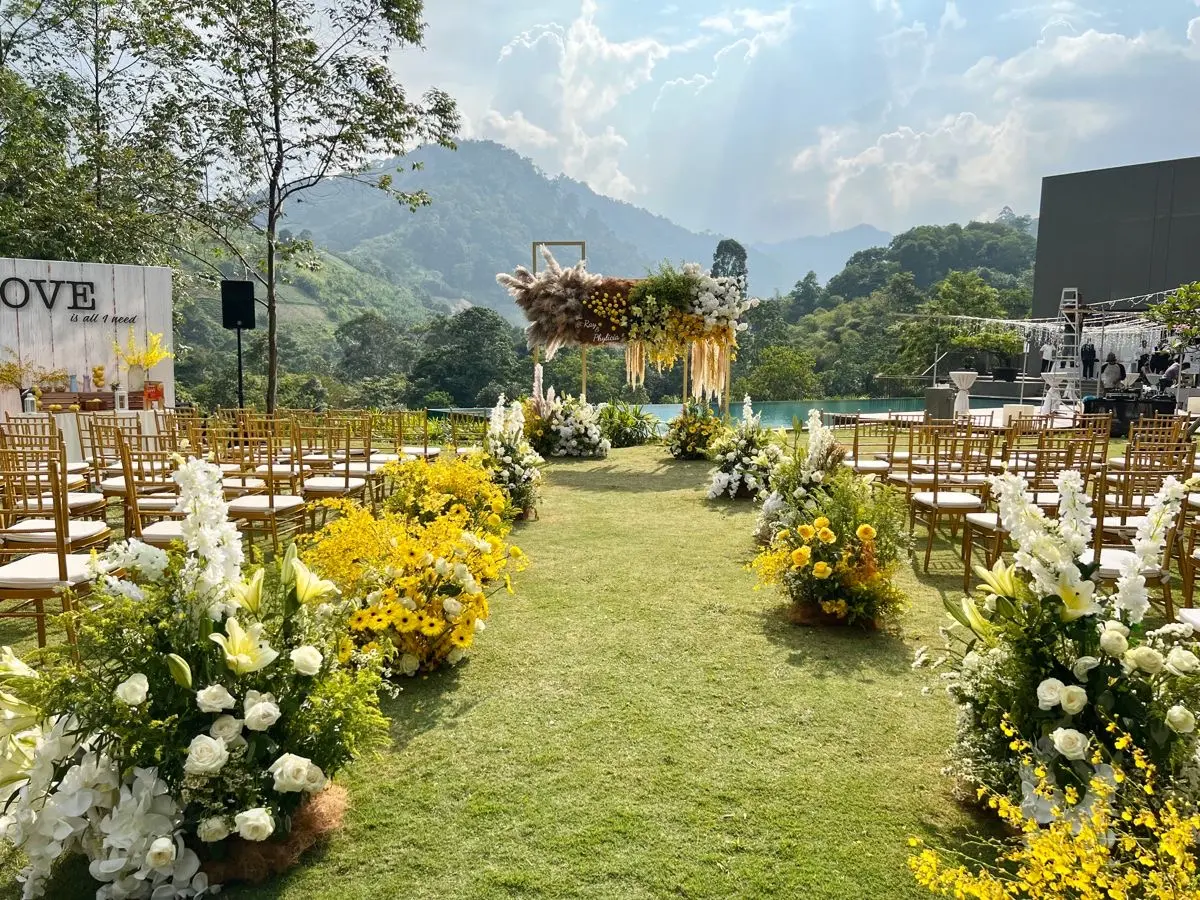 Outdoor wedding ceremony styled with yellow and white florals against a mountain view